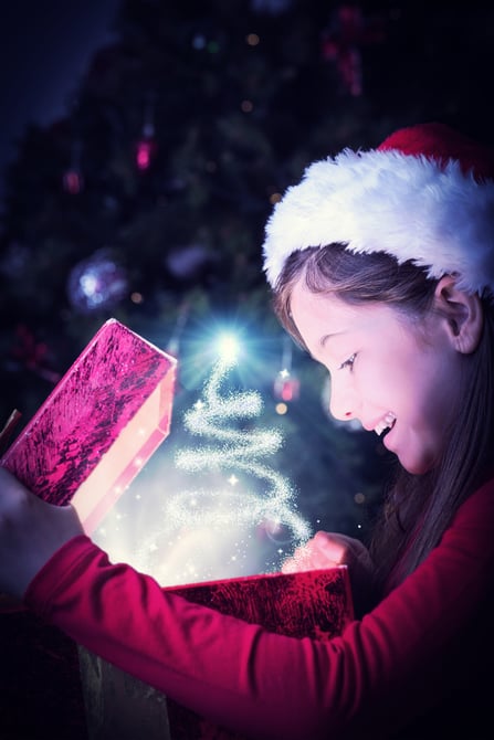 Little girl opening a magical christmas gift against christmas tree design